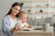 © Prostock-studio - Remote Career. Young Mom With Baby On Hands Using Smartphone And Laptop