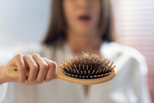 Hairloss Concept. Worried Woman Holding Comb Full Of Fallen Hair After Brushing