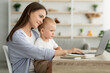 © Prostock-studio - Online Education. Young Mother Holding Baby And Study With Laptop At Home