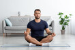 © Prostock-studio - Serious calm concentrated young caucasian muscular man with closed eyes sits on floor in lotus position, practices yoga
