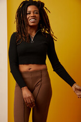 Studio portrait of smiling woman with dreadlocks against yellow background