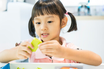 asian girl child having fun playing with colorful plastic blocks indoor at play school