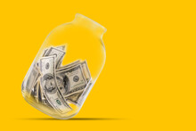 Many 100 US Dollars Bank Notes In A Glass Jar Isolated On Yellow Background