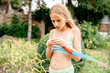 © Iryna - Happy preteen girl playing with gymnastic ribbon outdoor. Young lady with gymnastic tape played in a summer park or backyard. She is dressed in a green short top and shorts, colorful ribbon.