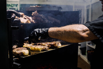 Chef cooking stake beef at barbecue party outdoor in the backyard - Focus on man arm