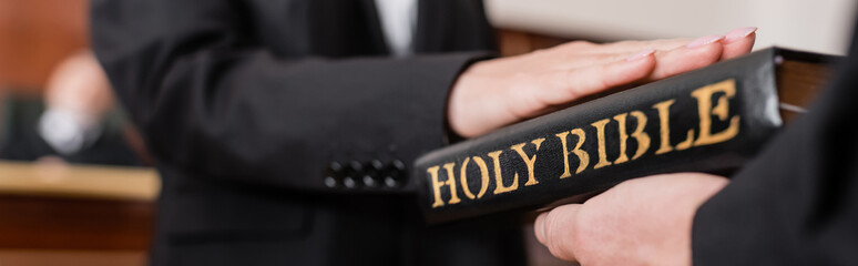 cropped view of woman giving swear on bible in court during litigation, banner