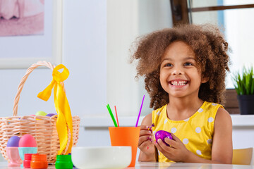 Wall Mural - Little with wide smile Black girl paint Easter eggs for Holiday