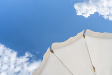 Bottom View On White Beach Or Pool Umbrella And Blue Sky With Small Cloudy. Copy Space. Holiday, Vacation, Travel Concept