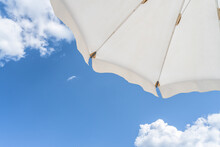 Bottom View On White Beach Or Pool Umbrella And Blue Sky With Small Cloudy. Copy Space. Holiday, Vacation, Travel Concept