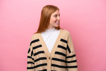 Wall Mural - Young redhead woman isolated on pink background looking side