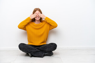 Poster - Young redhead woman sitting on the floor isolated on white background covering eyes by hands