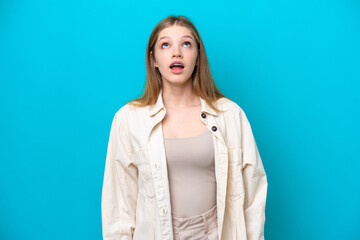 Teenager Russian girl isolated on blue background looking up and with surprised expression