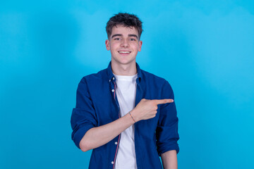 Poster - teen boy isolated on blue background pointing