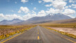 Asphaltierte Straße führt durch die Atacama Wüste entlang grüner steppen, roter Sandlandschaften sowie riesiger Vulkane und schneebedeckter Berge