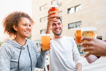 Cheerful friends cheering with beer in cafe