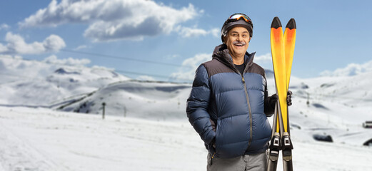 Sticker - Mature man holding a pair of skis on a mountain