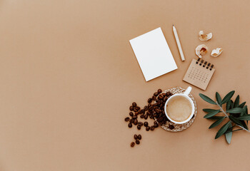 Wall Mural - Desktop mockup planner. Flat lay with calendar, blank card,  coffee cup and green olive leaves on brown background. Zero waste, eco friendly, natural organic concept.