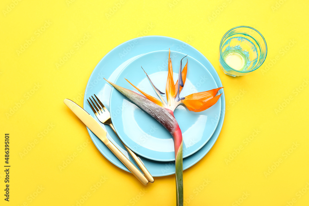 Simple table setting with bird of paradise flower on yellow background