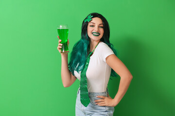 Young woman in wig with glass of beer on green background. St. Patrick's Day celebration