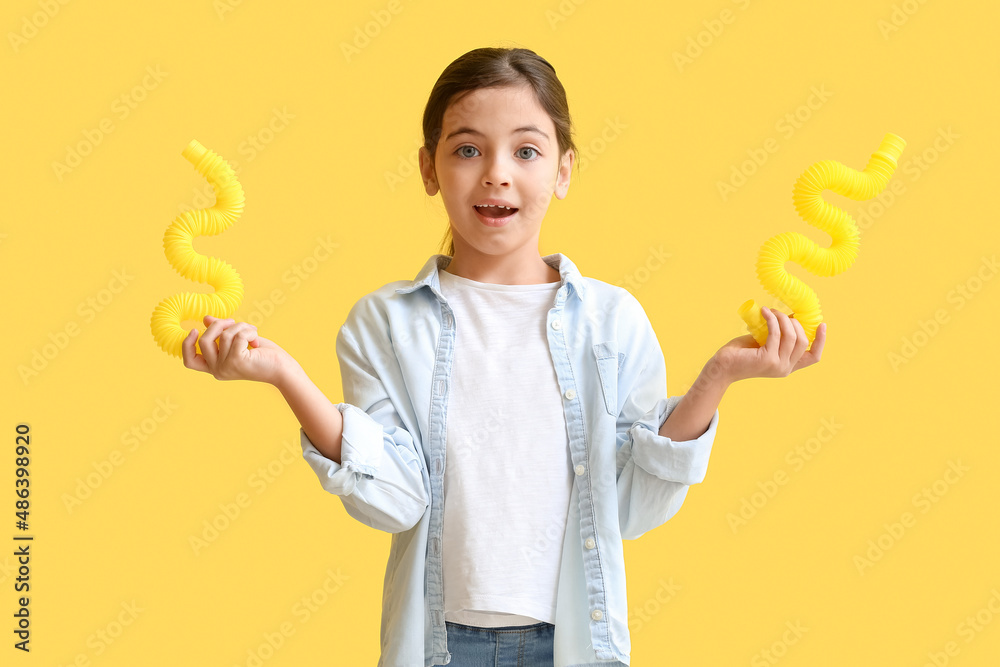 Little girl with Pop Tubes on yellow background