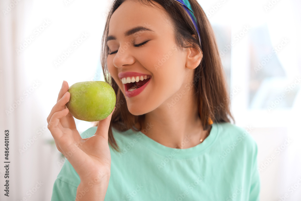 Young woman with green apple in kitchen, closeup