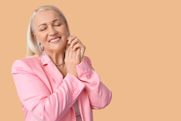 Wall Mural - Fashionable mature woman with closed eyes on beige background. International Women's Day celebration