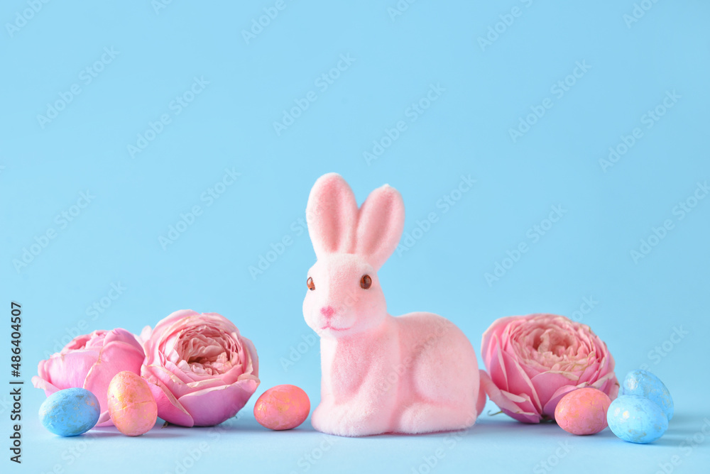 Cute Easter bunny with eggs and flowers on blue background