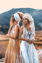 Wall Mural - two beautiful young stylish women wearing turban outdoors at sunset