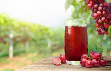 Canvas Print - Cool red grape juice with grape plantation background.