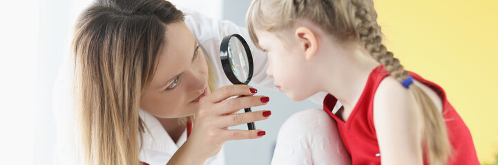 Wall Mural - Ophthalmologist conducts medical examination of girl eye through magnifying glass