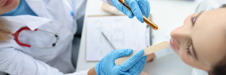 Woman ENT doctor conducts a medical examination of the throat of female patient top view