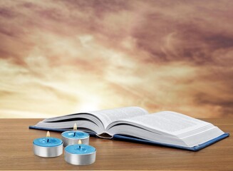 Wall Mural - Candles and an open book as a symbol of religion. holy book and morning sky. Reading holy book.