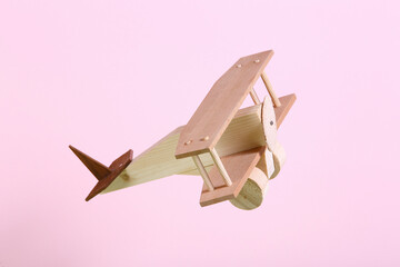 wooden toy airplane with pink pastel background