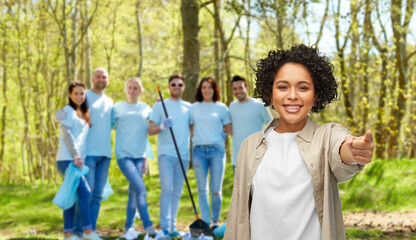 Poster - environment, volunteering and charity concept - happy smiling woman pointing finger to camera over group of volunteers working at park on background