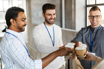 Sticker - business, people and corporate concept - happy smiling colleagues with conference badges drinking takeaway coffee at office