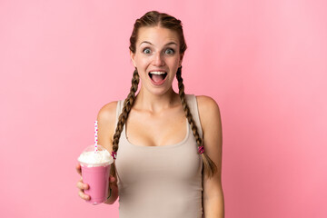 Wall Mural - Young woman with strawberry milkshake isolated on pink background with surprise facial expression