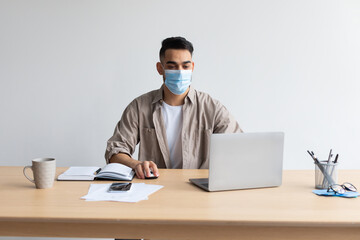 Wall Mural - Man in disposable facemask working on pc at home office