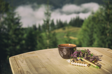 A cup of herbal tea and a notepad on a wooden table overlooking the mountains and forests