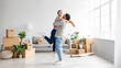 © Prostock-studio - Happy excited european millennial husband raises wife have fun in living room interior with cardboard boxes