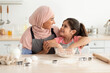 © Prostock-studio - Portrait Of Cute Little Girl Helping Islamic Mom Baking In Kitchen