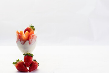 Fresas con nata en copa de cristal con fresas en la base de la copa tiradas