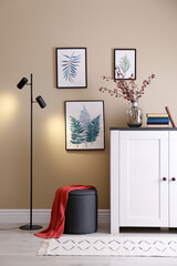 Poster - stylish ottoman, wooden cabinet and floor lamp in room. interior design