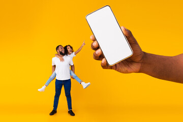 Wall Mural - Black dad and daughter showing empty smartphone screen for mockup