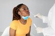 Young black woman getting nasal coronavirus swab test on grey studio background. Health care, medicine, new normal