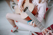 © Анна Молько - a cute little girl in a pink sweater is playing a baby guitar in her room. music training