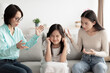 Asian girl covering ears, trying to hide from mother and grandmother scolding her at home