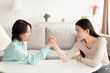 © Prostock-studio - Mature Asian mother and adult daughter arm wrestling, looking each other in eyes, fighting at home