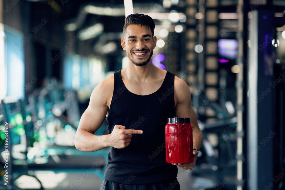 Bodybuilding Nutrition. Happy Arab Sportsman Pointing At Red Contrainer ...