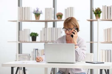 Wall Mural - senior businesswoman or freelance using laptop computer and talking about work on phone