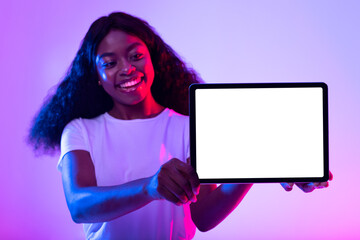 Poster - Millennial African American lady presenting mockup for advertisement on tablet screen in neon light, selective focus